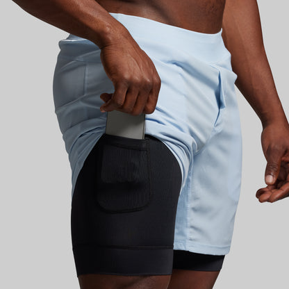 Person wearing a light blue athletic short with black liner on a neutral background
