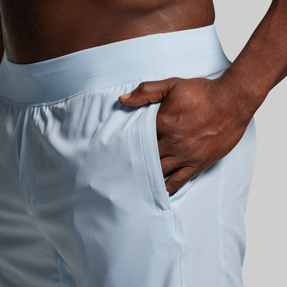 Light blue athletic shorts with a hand in the pocket against a neutral background.