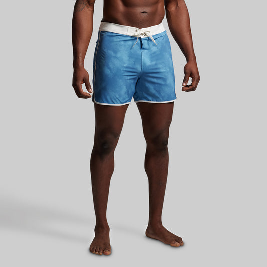 Person wearing blue swim shorts on a gray background