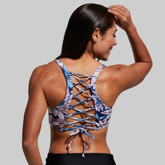Woman wearing a colorful strappy bikini top with a gray background