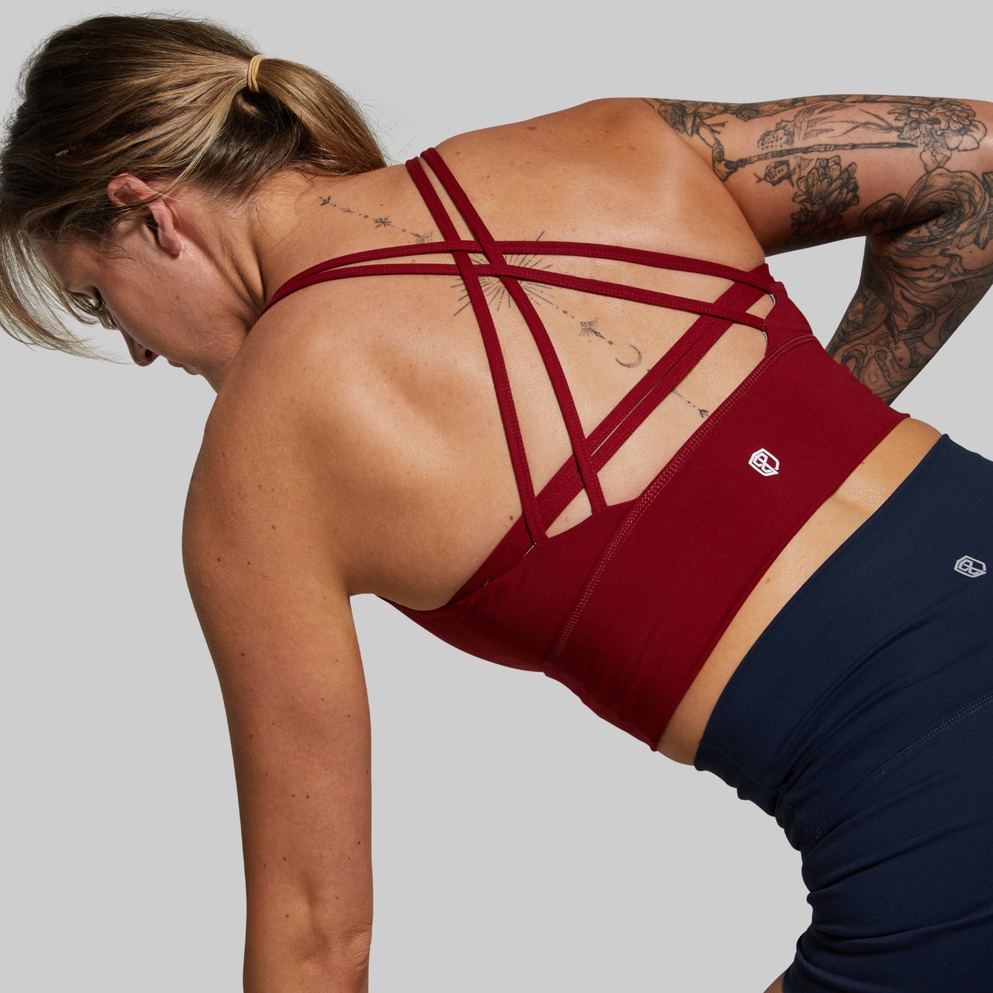 Person wearing a red sports bra and navy leggings on a light gray background