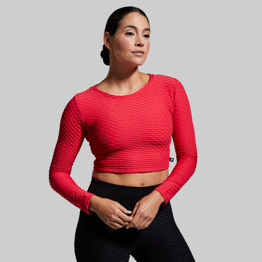 Woman wearing a red long-sleeve athletic top against a gray background
