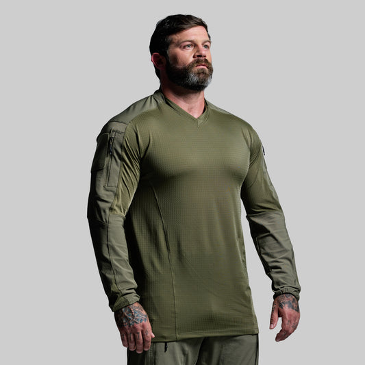 Man wearing a green long-sleeve shirt against a gray background