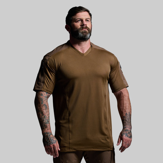 Man wearing a brown tactical shirt on a gray background