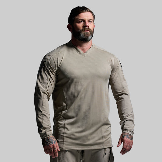 Man wearing a beige tactical shirt on a gray background