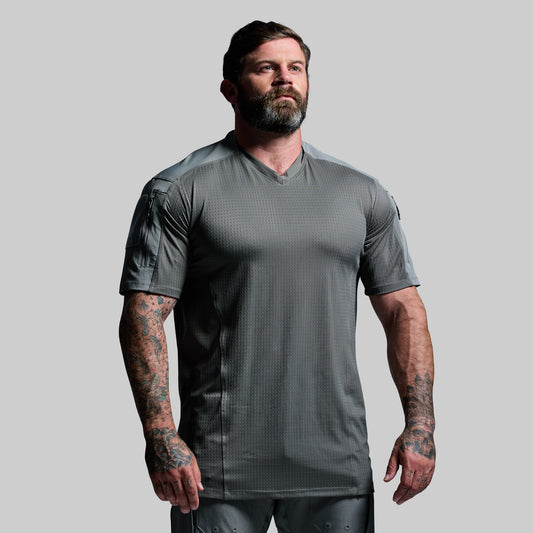 Man wearing a gray tactical shirt on a plain background