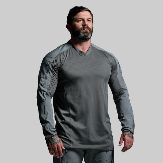 Man wearing a gray tactical long-sleeve shirt on a light gray background
