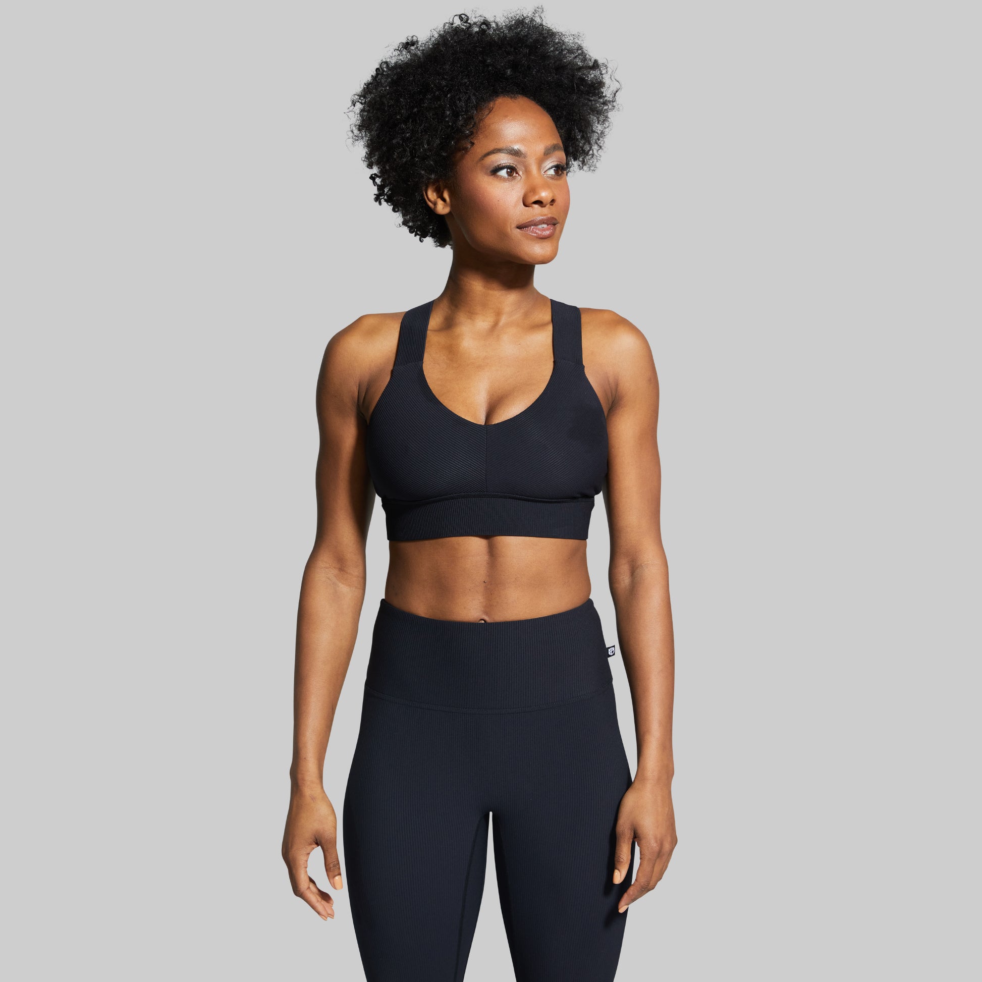 A woman wearing a black All or Nothing Sports Bra with wide straps and a ribbed design.