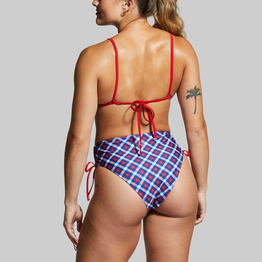 Woman wearing a red and blue checkered bikini with a plain background