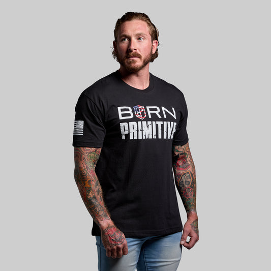 Man wearing a black t-shirt with 'Born Primitive' logo on a gray background