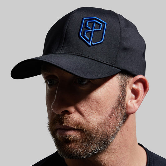 Man wearing a black cap with a blue logo on a gray background