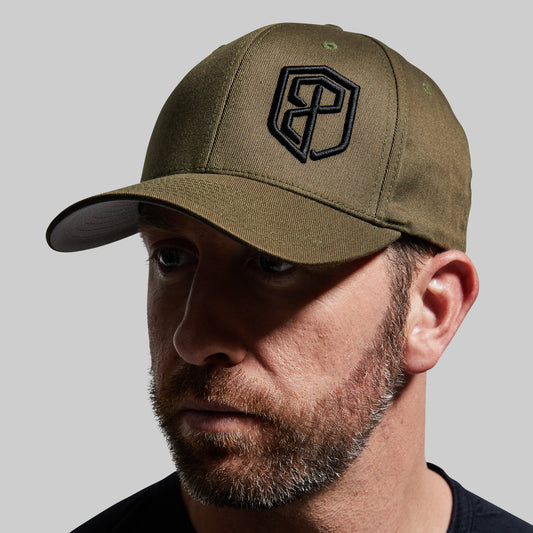 Man wearing a green cap with a logo on a gray background