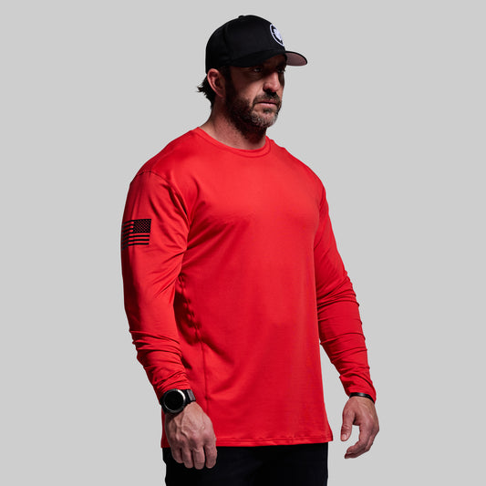 Man wearing a red long-sleeve shirt and black cap on a gray background