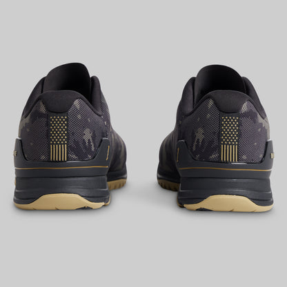A pair of athletic sneakers shown from the rear, featuring a dark gray and black camouflage pattern with gold accents on the heel stripes and midsole, and a beige outsole.