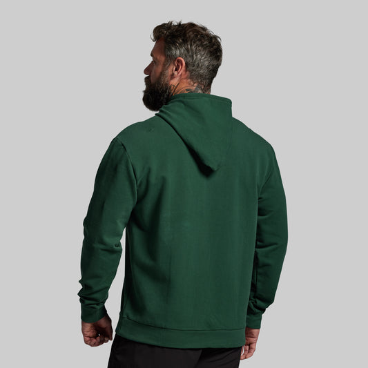 Man wearing a green hoodie from behind on a gray background