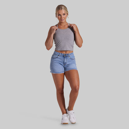 A woman modeling a gray sleeveless crop top and light blue denim shorts against a solid light gray background.