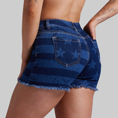 A close-up back view of a model wearing blue denim shorts with horizontal stripes and embossed star details, set against a solid gray background.