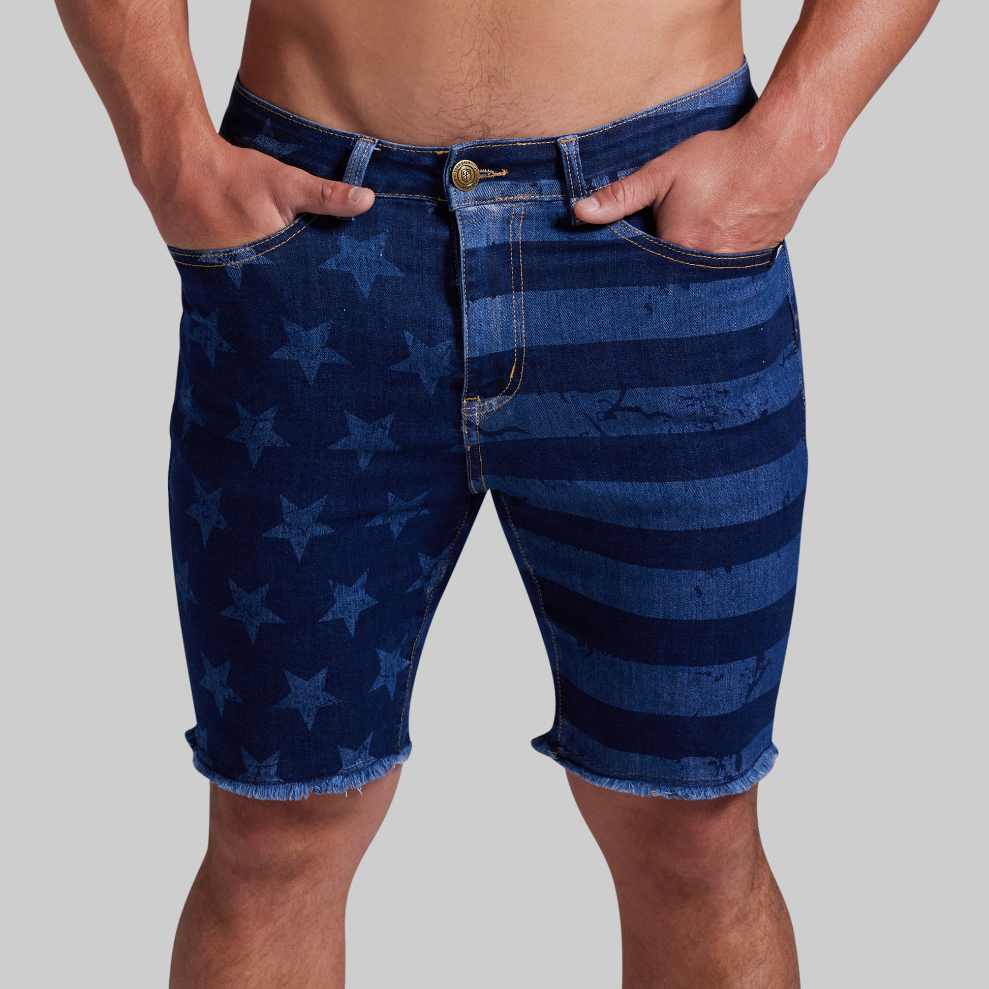 Men's denim shorts featuring a blue and navy American flag-inspired pattern with stars and horizontal stripes, shown on a model against a solid gray background.
