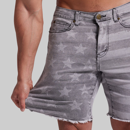Gray denim shorts with a faded white star pattern and frayed hems, shown on a model against a light gray background.