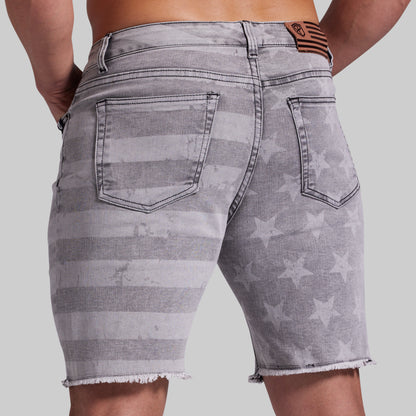 Gray denim shorts with a faded horizontal stripe and star pattern, shown from the back on a model against a light gray background.