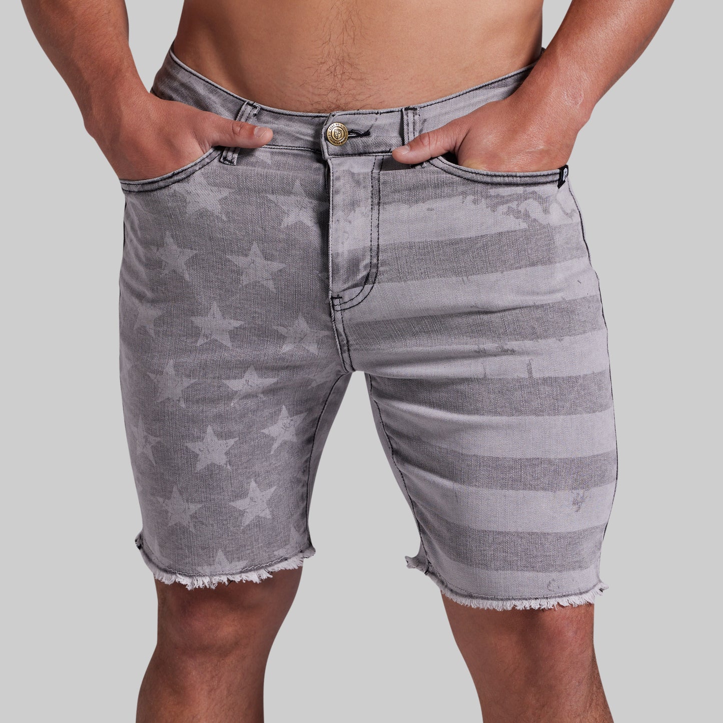Gray denim shorts with a faded star and stripe pattern, featuring a frayed hem and side pockets, shown on a model against a light gray background.