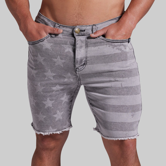 Gray denim shorts with a faded star and stripe pattern, featuring a frayed hem and side pockets, shown on a model against a light gray background.