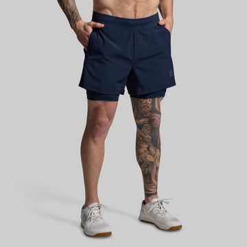 Person wearing navy blue athletic shorts on a gray background