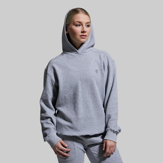 Person wearing a gray hoodie and pants on a plain background