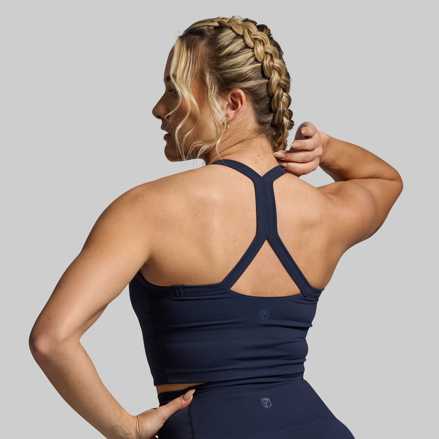 Woman wearing a navy blue sports bra and leggings on a gray background