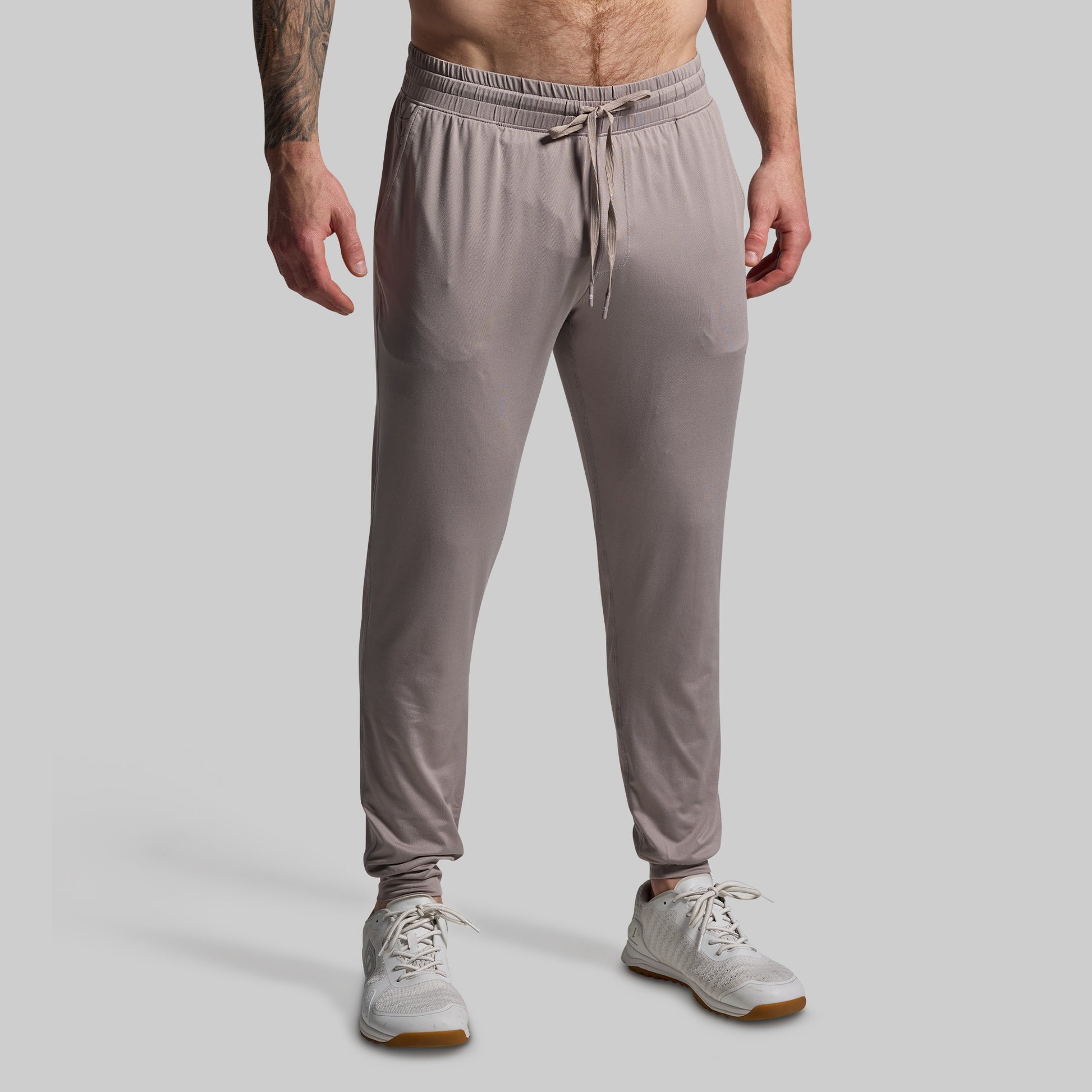 Person wearing light gray jogger pants on a plain background
