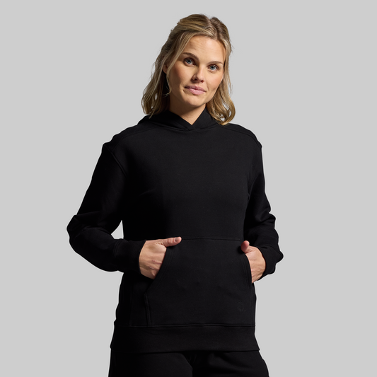 Woman wearing a black hoodie against a gray background
