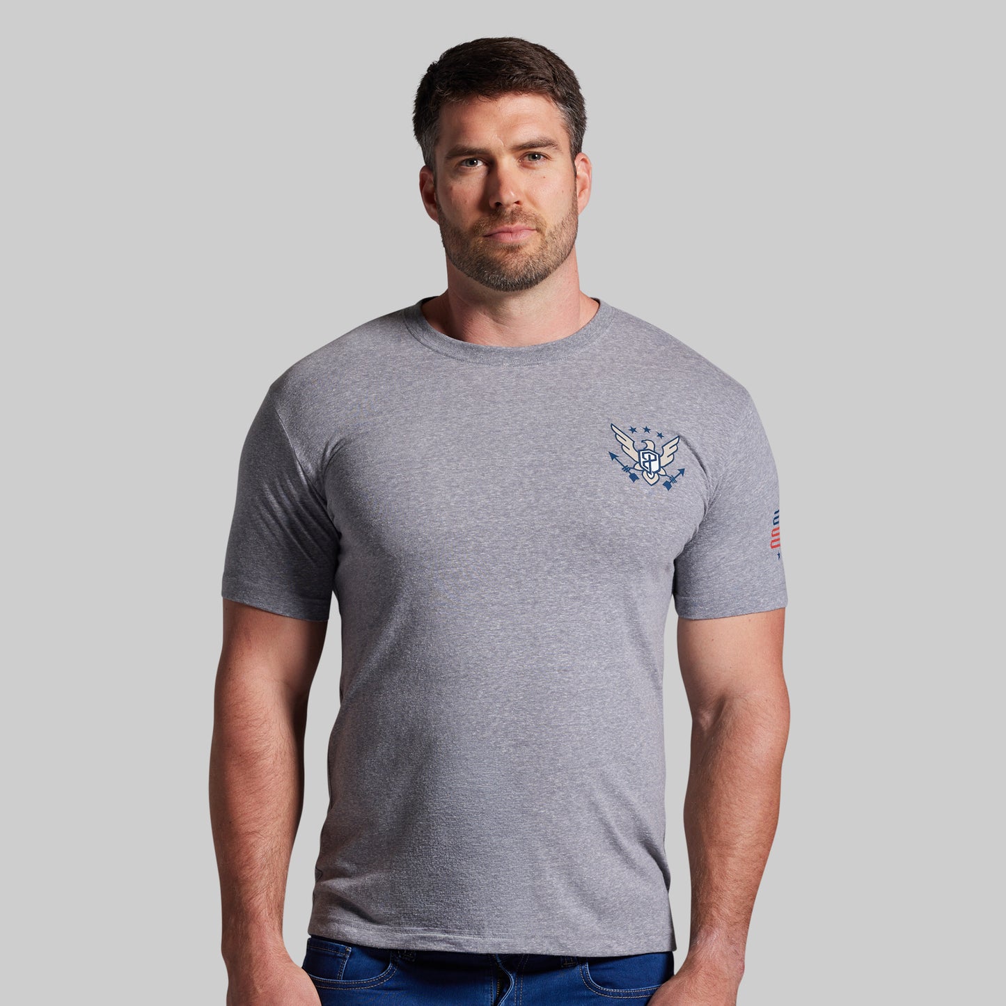 Man wearing a gray t-shirt with a logo on a plain background