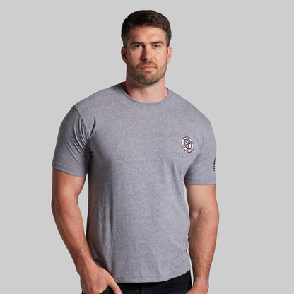 Man wearing a gray t-shirt with a logo on a light gray background