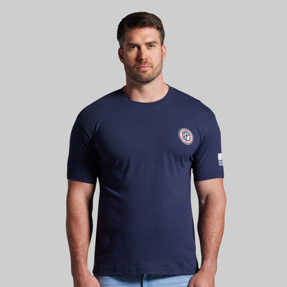 Man wearing a navy blue t-shirt with a logo on a gray background