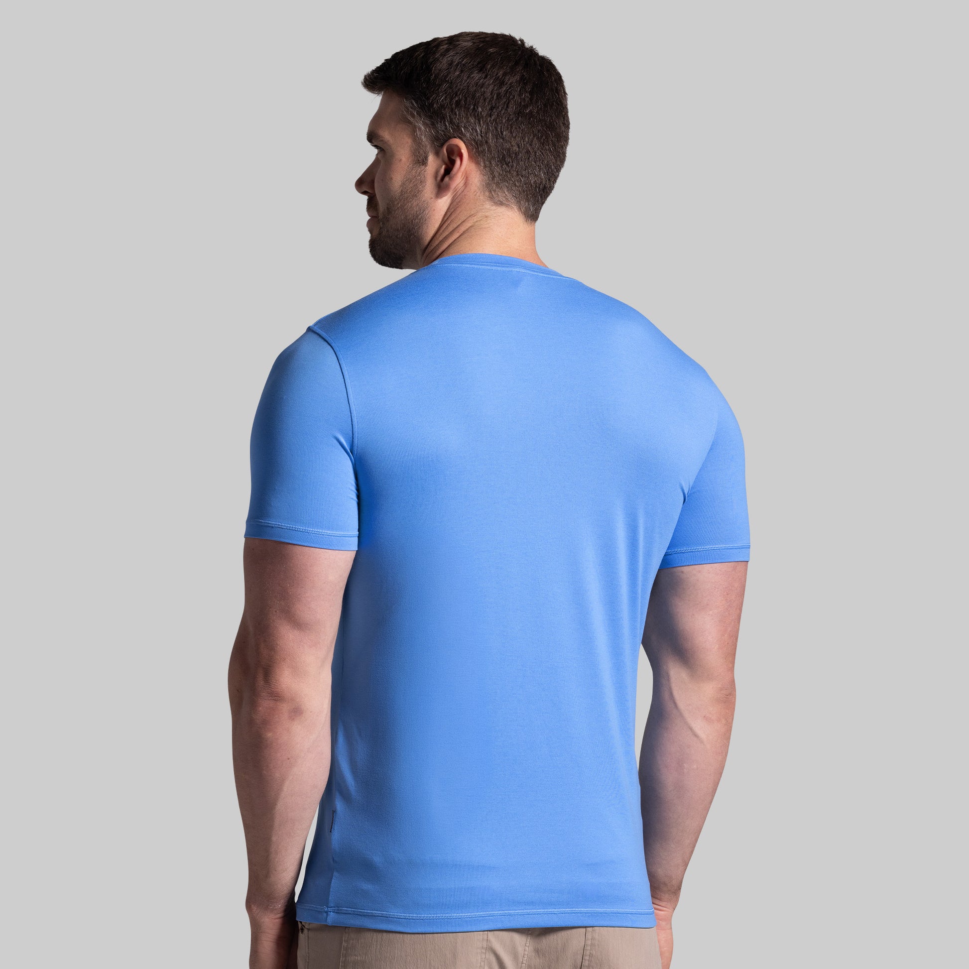 Man wearing a blue t-shirt against a gray background