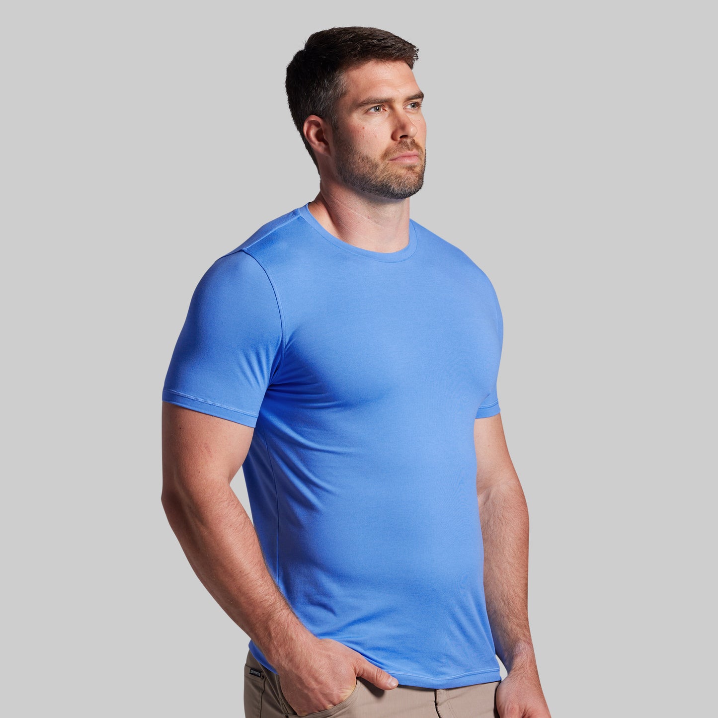 Man wearing a blue t-shirt against a gray background