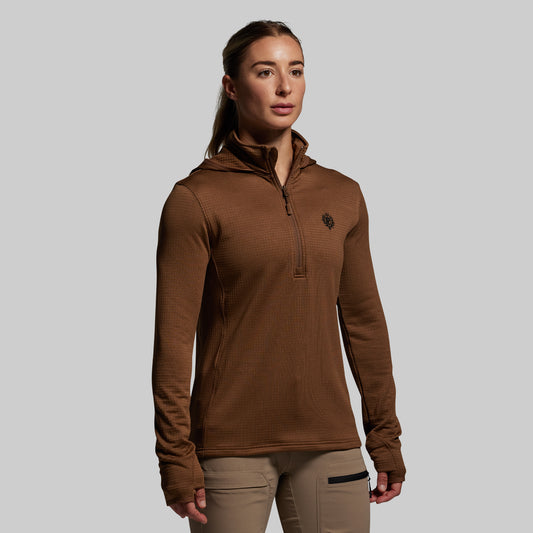 Woman wearing a brown long-sleeve hoodie with a small logo on a gray background