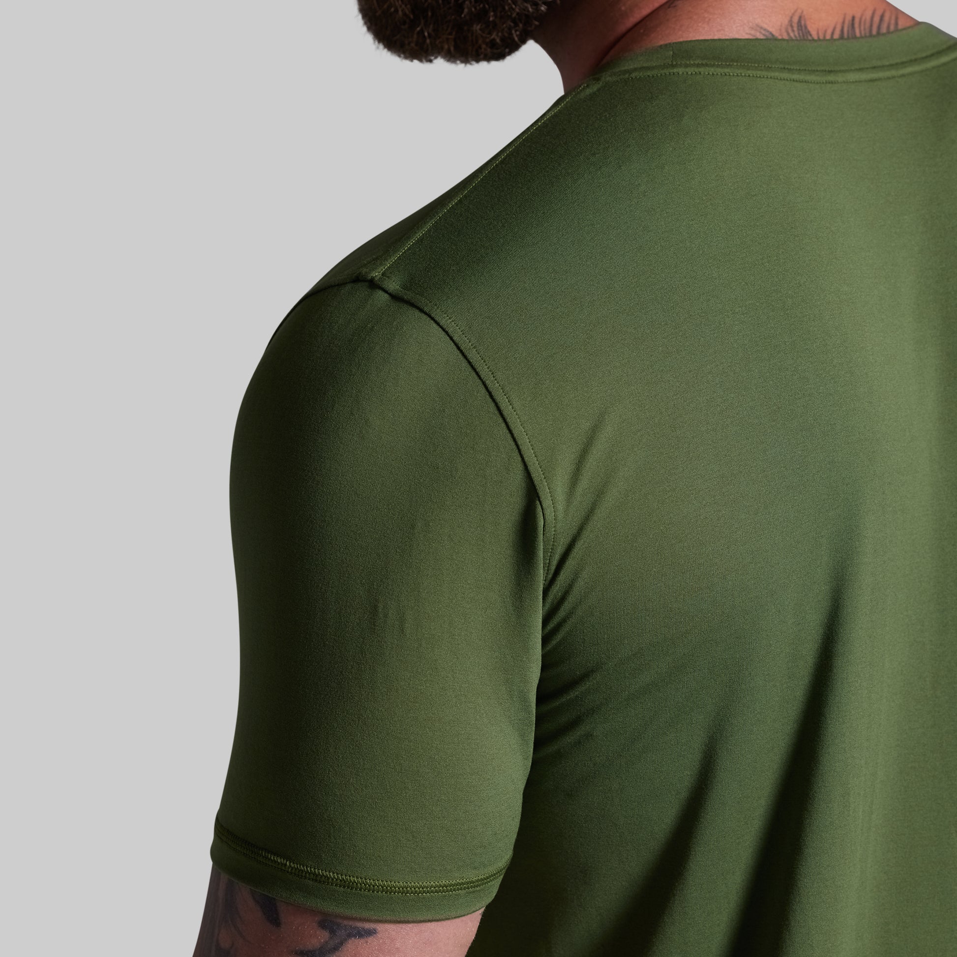 Person wearing a green t-shirt on a gray background
