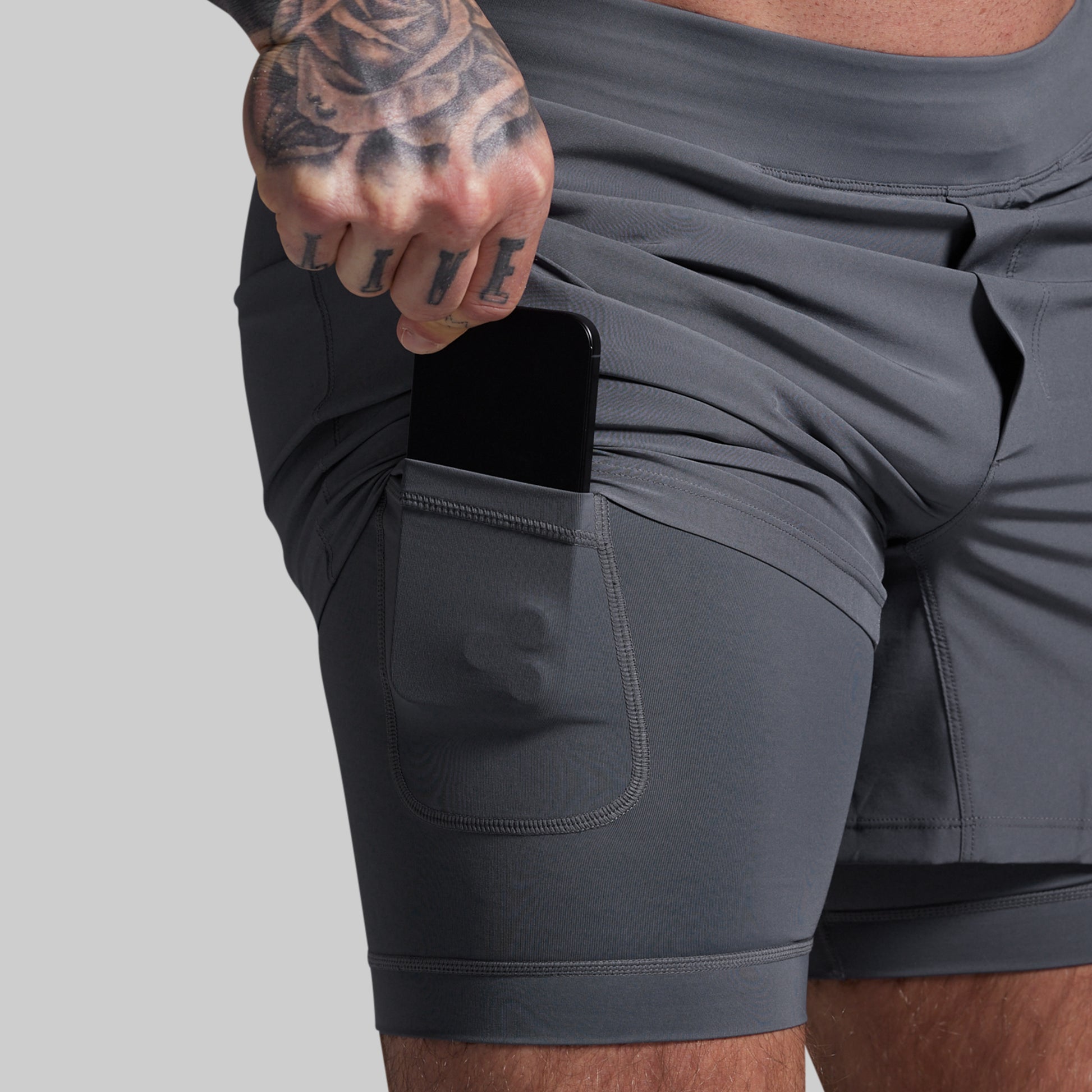 Person wearing gray athletic shorts with a pocket on a light gray background