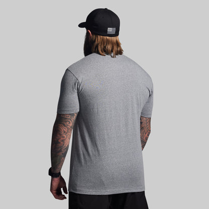 Man wearing a gray t-shirt and black cap with an American flag design on a light gray background