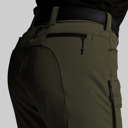 Close-up of olive green outdoor pants with a black belt, showing the back pocket, zipper details, and side cargo pockets on a neutral gray background.