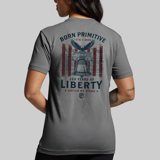 Person wearing a gray t-shirt with 'Born Primitive' and '250 Years of Liberty' design on the back.