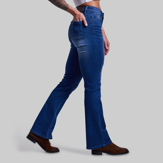 Person wearing blue flared jeans on a gray background