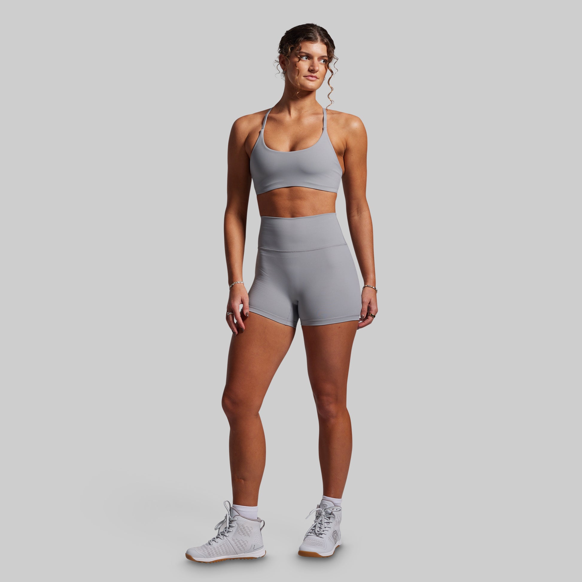 Woman wearing a gray athletic outfit on a light gray background