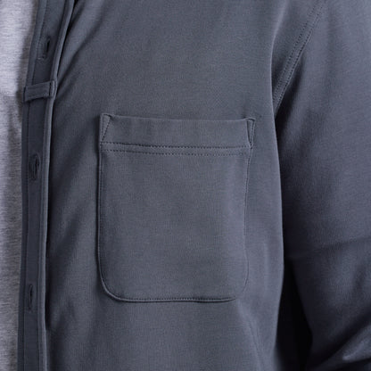 Close-up of a dark gray long-sleeve button-up shirt with a chest pocket, worn over a light gray undershirt.