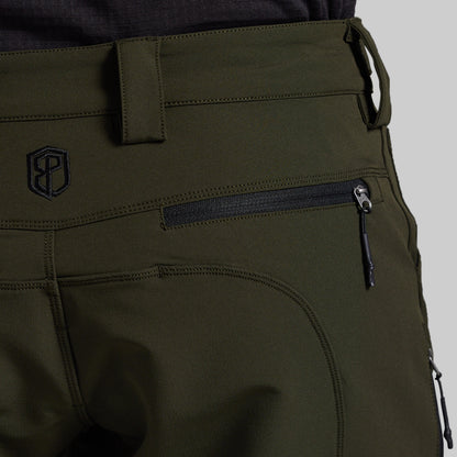 Close-up of olive green outdoor pants showing a zippered pocket, belt loop, and a black embroidered logo on the back.