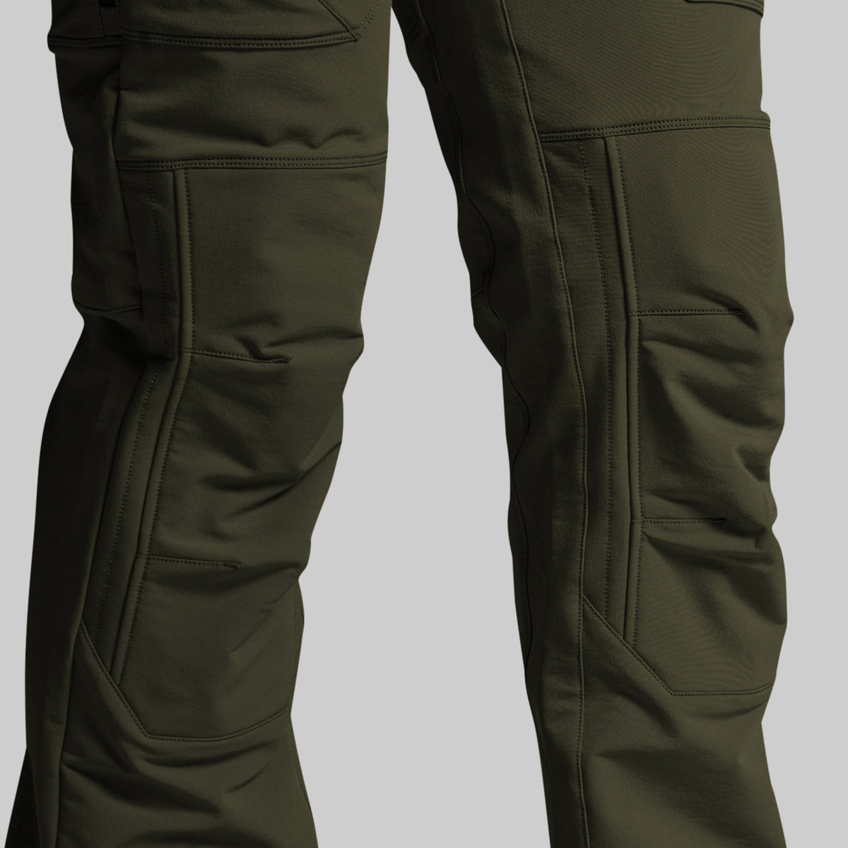 Close-up of dark olive green technical pants showing the leg construction, cargo pockets, and reinforced knee panels against a solid gray background.