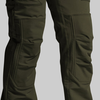 Close-up of dark olive green technical pants showing the leg construction, cargo pockets, and reinforced knee panels against a solid gray background.