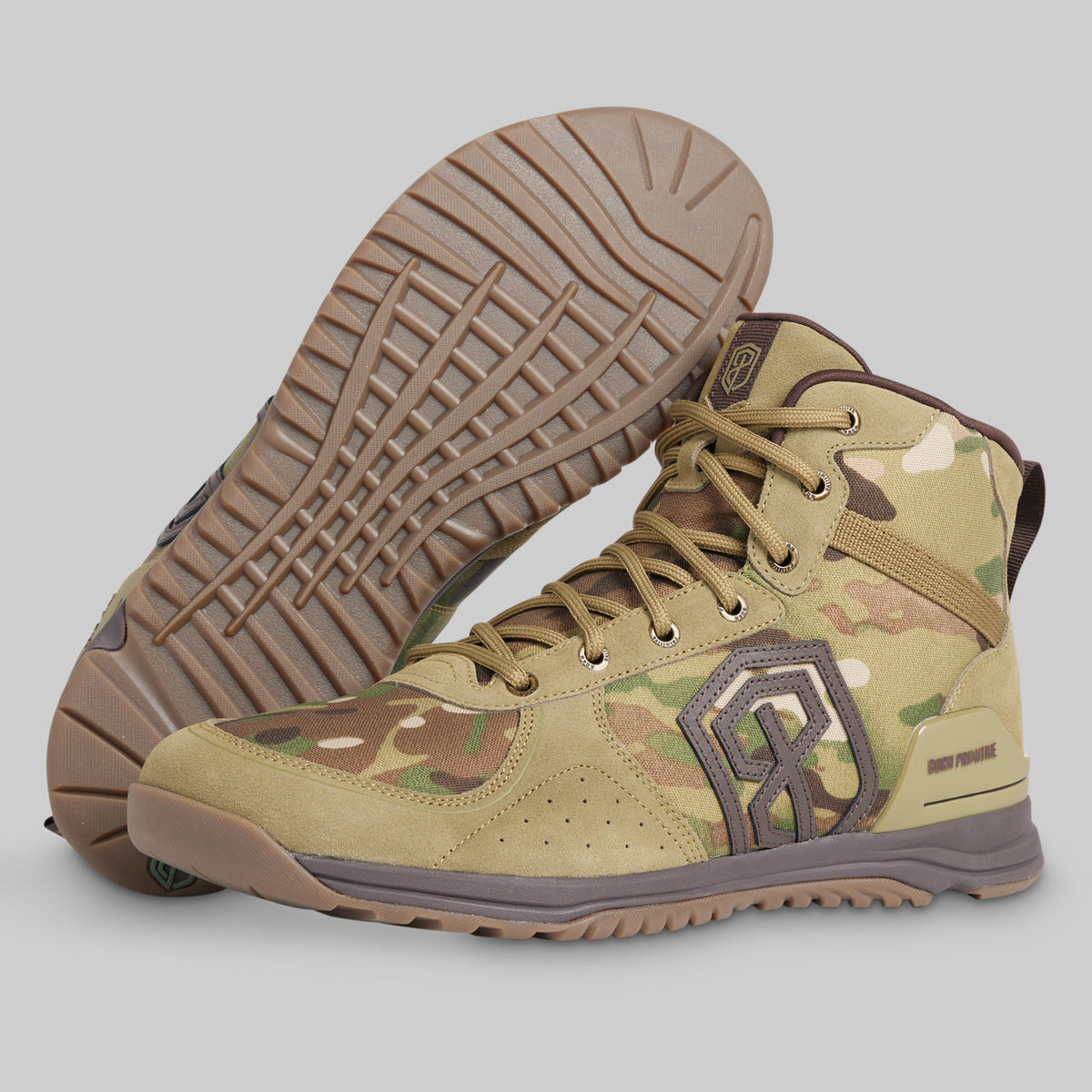 A pair of tactical high-top boots in a tan and brown camouflage pattern, with one boot showing the textured outsole and the other showing the side profile with a gray logo.