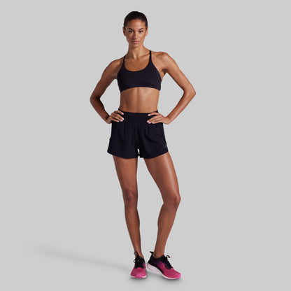 Woman wearing a black sports bra and shorts on a gray background